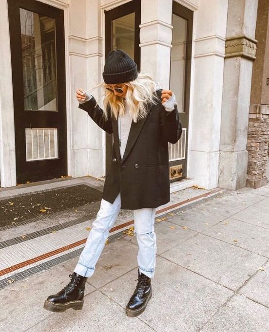 a neutral turtleneck, bleached blue jeans, black combat boots, a black oversized blazer and a black beanie for a comfy look
