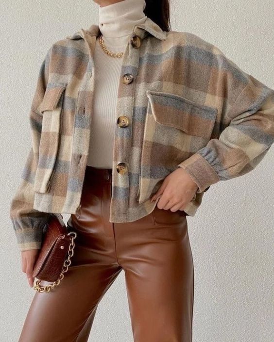 a neutral turtleneck, brown leather pants and a matching bag, a plaid cropped shirt jacket and a gold chain necklace