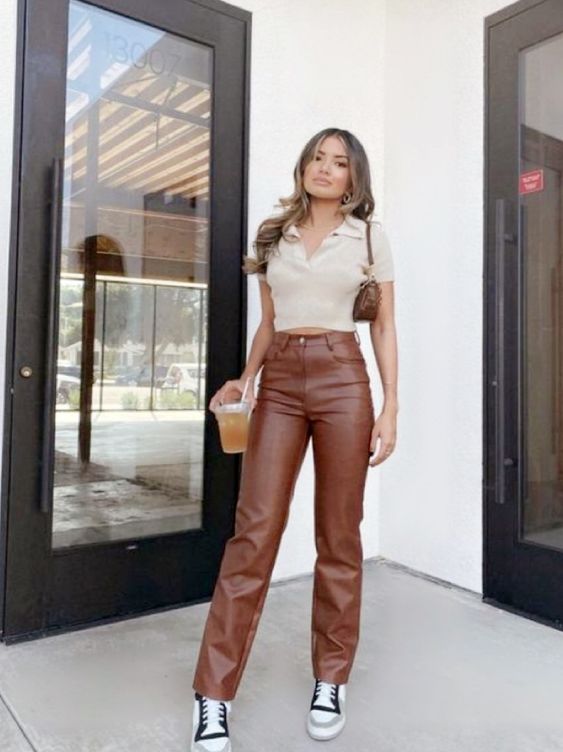 a neuttal crop top, brown leather pants, white and grey sneakers, a brown mini bag are a lovely look