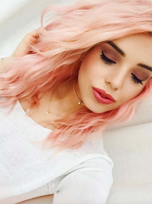 a side part, shoulder length cut and incredibly beautiful pinkish peach hair to contrast with dark brows and lashes