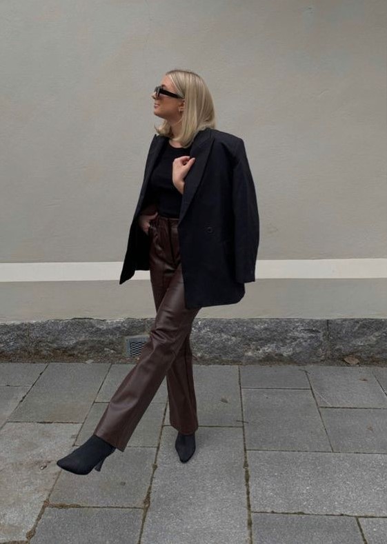 a simple and chic work outfit with a black top, a black blazer and boots, brown leather pants will never go out of style