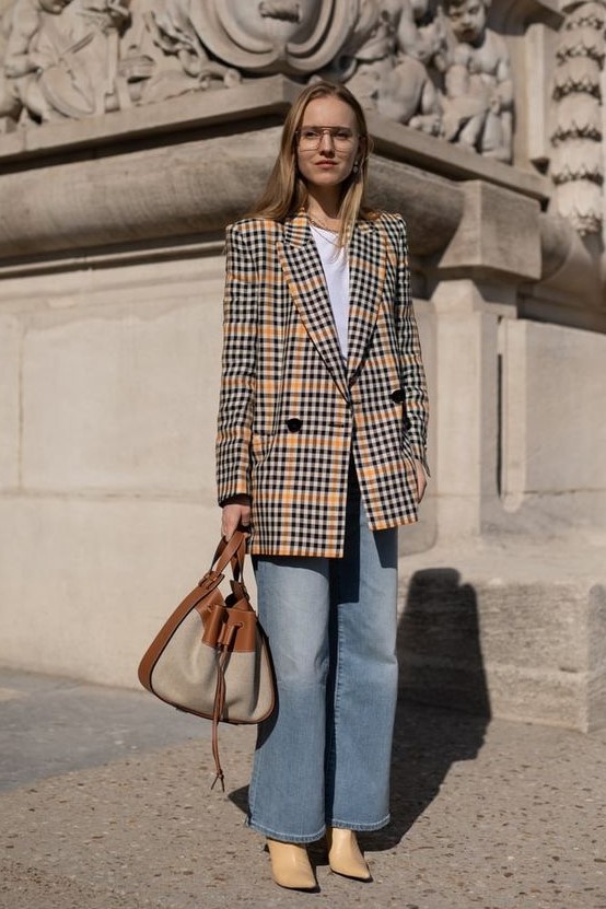a white t-shirt, an oversized beige plaid blazer, blue wideleg jeans, tan heeled boots and a two-tone bag