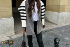 a white t-shirt, black jeans, a grey oversized blazer, neutral trainers, a black bag and a Breton stripe sweater over the shoulders