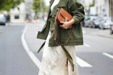 a white top and neutral midi skirt with a slit, brown strappy shoes, a green utility jacket and a brown bag