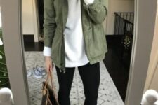 a white turtleneck, black leggings, black trainers, a green utility jacket, a large printed tote are a lovely look