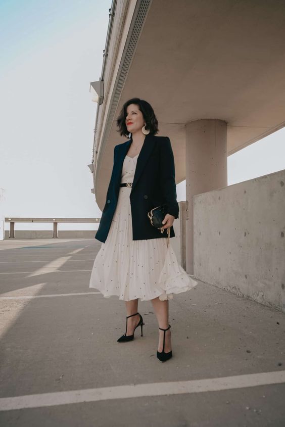 a beautiful feminine look with a creamy polka dot midi dress, an oversized black blazer, black T-strap shoes and a clutch