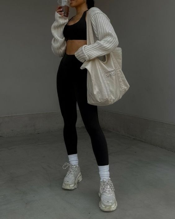 a sporty look with a black crop top, black leggings, white socks and grey trainers, a creamy cropped cardigan and a canvas bag