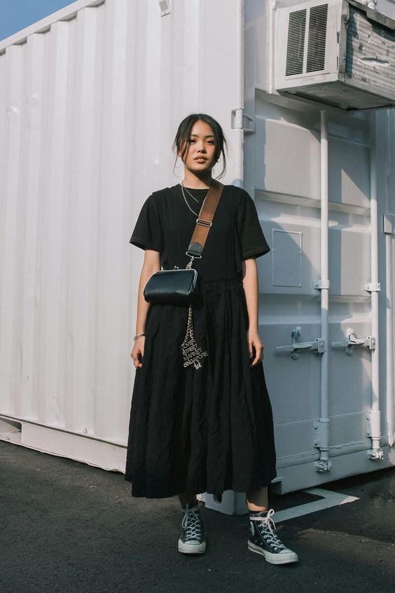a black t shirt, black pleated midi skirt, black high top sneakers, a catchy black bag and layered necklaces