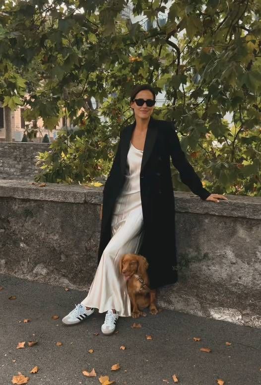 an ivory slip maxi dress, a black coat, white Adidas sneakers are all you need for an elegant and comfy look