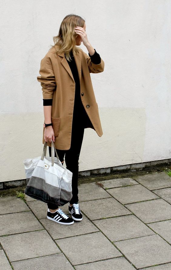 a black long sleeve top, black jeans, black Gazelle sneakers, an oversized beige blazer and a striped tote for spring