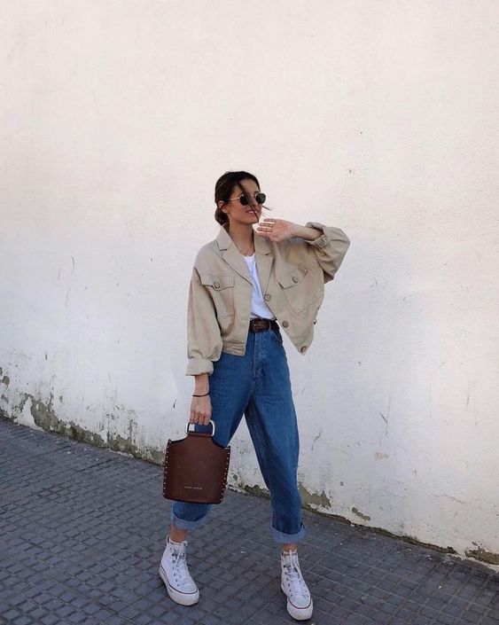 a white t-shirt, blue baggy jeans, white high top sneakers, a tan cropped denim jacket and a brown bag