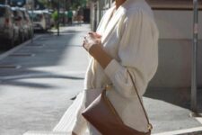 10 a neutral mini skirt, a neutral cardigan tucked into the skirt, a brown baguette bag plus statement earrings