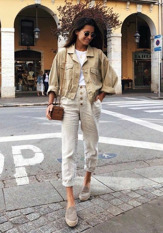 a wihte t-shirt, neutral linen pants, grey loafers, a tan cropped denim jacket and a brown crossbody bag
