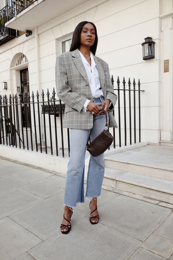 a chic outfit with a white shirt, an oversized grey plaid blazer, blue cropped jeans, black strappy shoes and a brown baguette bag