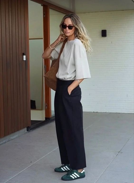 a minimalist outfit with a dove grey t-shirt, black trousers, green Gazelle sneakers, a brown tote for spring