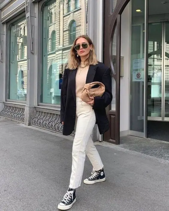 a blush top, white jeans, black high top sneakers, an oversized black blazer, a beige woven bag for every day