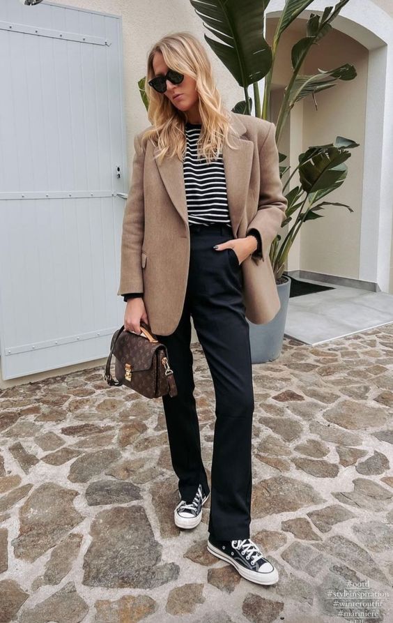 a Breton stripe top, black pants and black high tops, a beige oversied blazer and a brown printed bag for work