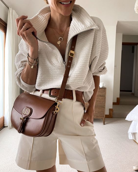 a neutral lok with a zip polo shirt, neutral shorts, a brown belt and a brown crossbody bag