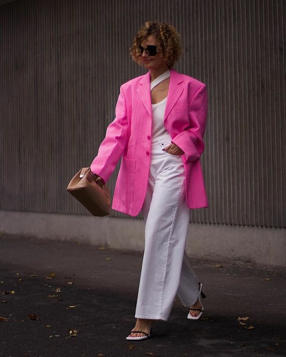 a spring work outfit with a catchy top, white wideleg jeans, white shoes, a hot pink oversized blazer and a brown bag