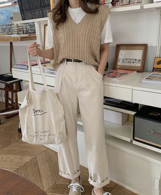a comfy spring look with a white tee, a beige knit waistcoat, neutral trousers, tan sneakers and a neutral canvas bag