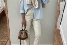 20 a blue shirt, neutral jeans, neutral trainers and a jumper over the shoulders, a two-tone bag for spring