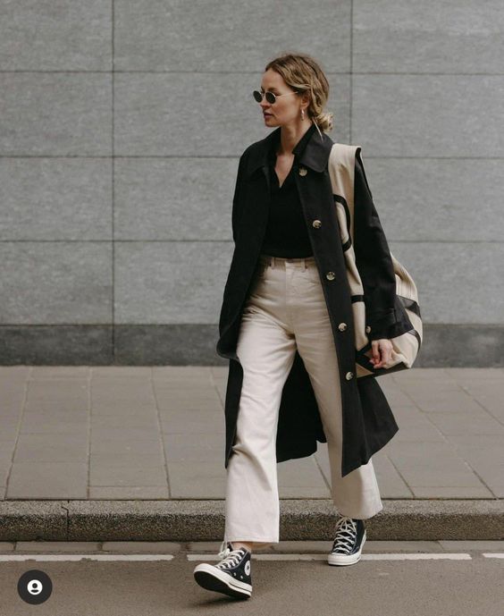 a monochromatic spring outfit with a black shirt, white jeans, black sneakers, a black trench and a large printed bag