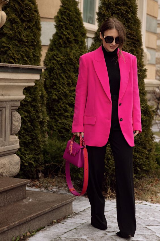 a total black look with a turtleneck, trousers and shoes, a hot pink oversized blazer and a fuchsia bag