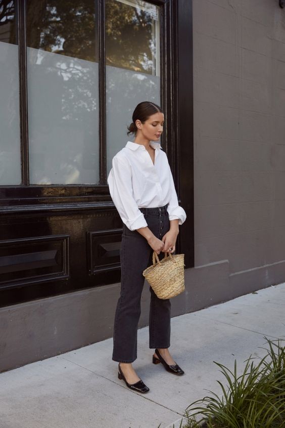 a French chic look with a white shirt, black button up jeans, black slingbacks and a straw bag