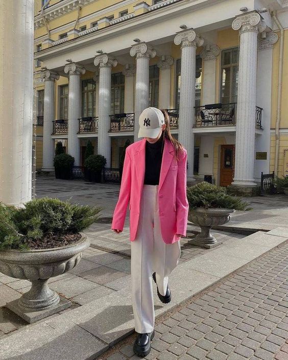 a black turtleneck, white trousers, black shoes, a hot pink blazer, a white cap are a cool eclectic look for spring