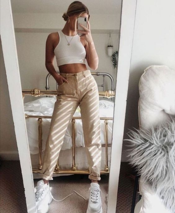 a white crop top, tan jeans, white trainers and a necklace are a lovely look for summer