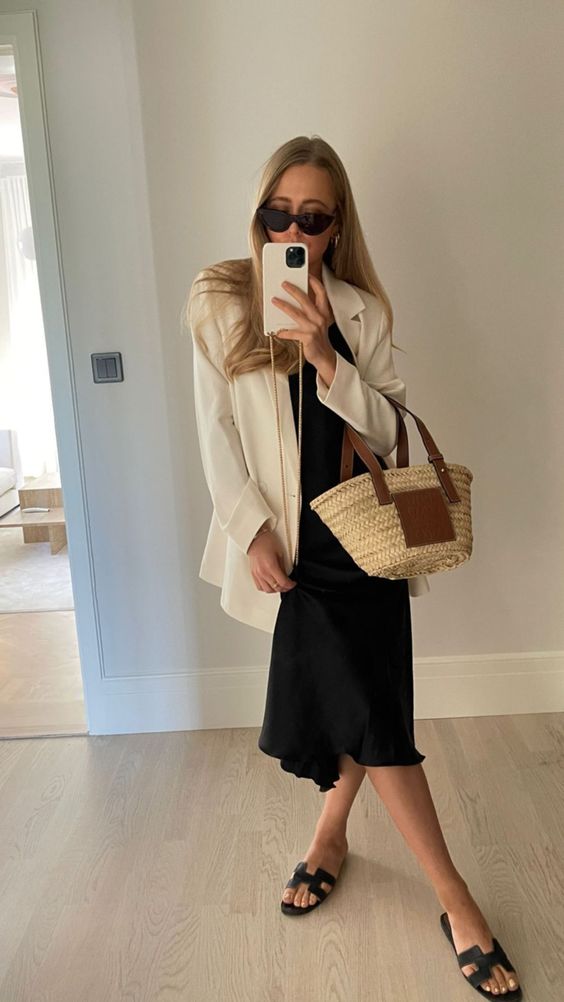 a black slip midi dress, a creamy oversized blazer, black slippers and a small straw bag for summer