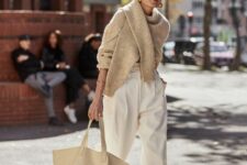 24 a neutral outfit with white high-waisted pants, neutral slippers, a tan sweater, a neutral canvas tote for a cold day