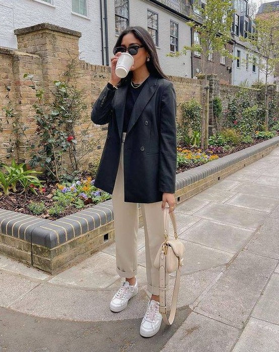 a work outfit with a black t-shirt, an oversized black blazer, tan trousers, a tan bag, white sneakers is amazing for spring