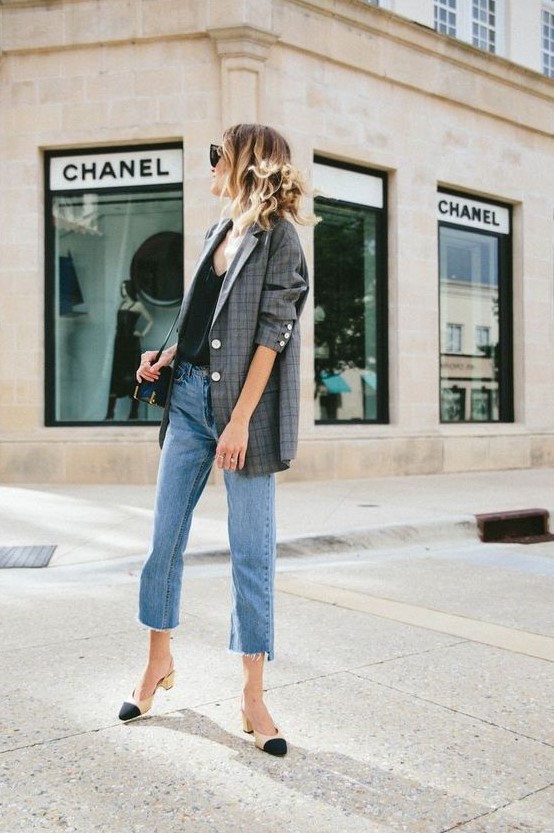 a black top, blue jeans with a raw hem, a plaid oversized blazer, black and creamy shoes