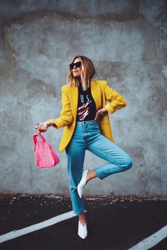 a black printed t-shirt, blue jeans, white shoes, a yellow blazer and a pink bag are a super cool look for spring