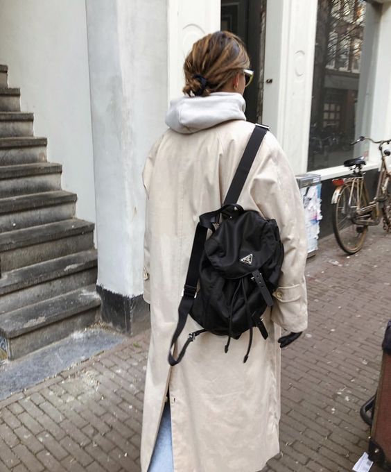 a grey hoodie, a tan trench, blue jeans and a black backpack are a great look for a cold day