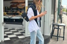 30 an oversized white button down, bleached jeans, a black jumper, neutral Adidas sneakers and a small black bag