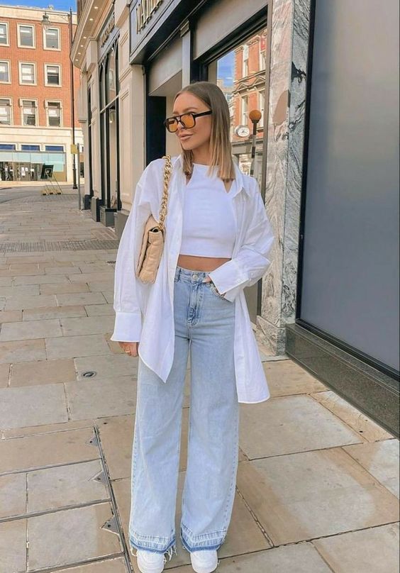 a white top top, an oversized white shirt, bleached high waisted jeans, white sneakers and a beige bag with chain for spring
