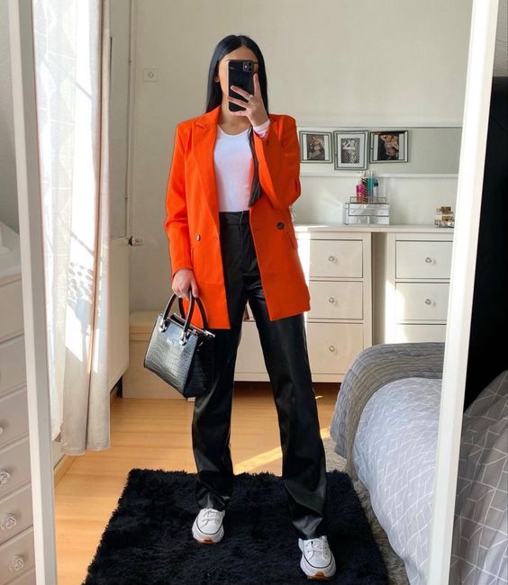 a white crop top, black leahter pants, white trainers, an orange blazer and a black bag are a great combo