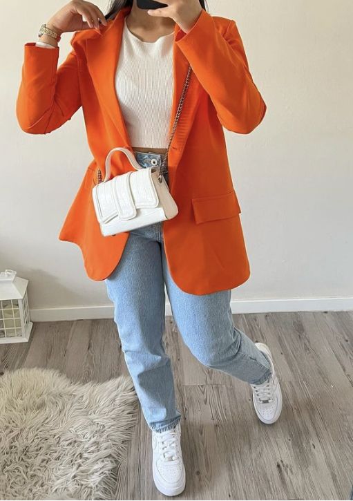 a white crop top, trainers and a bag, blue jeans, an orange blazer are a gerat combo for spring and fall