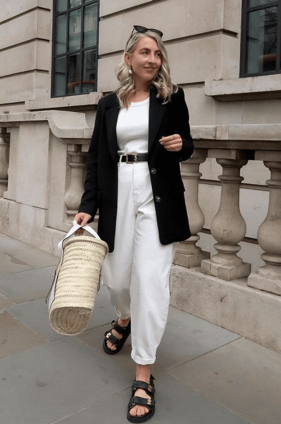 a white top, baggy jeans, a black blazer, black sandals and a straw bag for a relaxed spring look