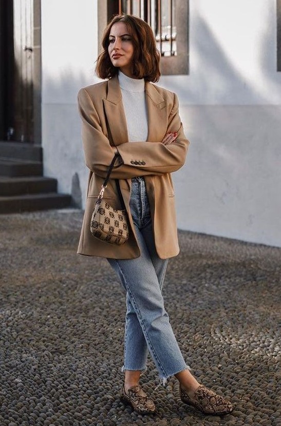 a lovely casual outfit with a white turtleneck, blue cropped jeans, snakeskin print loafers and a beige oversized blazer plus a printed bag