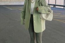 36 dark green leggings, a light green oversized blazer and a pale green bag, a white top, white trainers and socks and a white cap