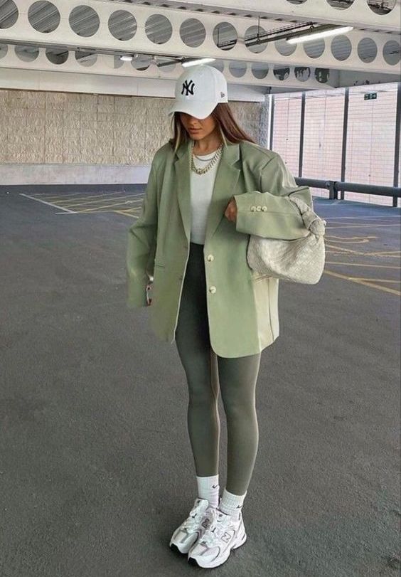 dark green leggings, a light green oversized blazer and a pale green bag, a white top, white trainers and socks and a white cap