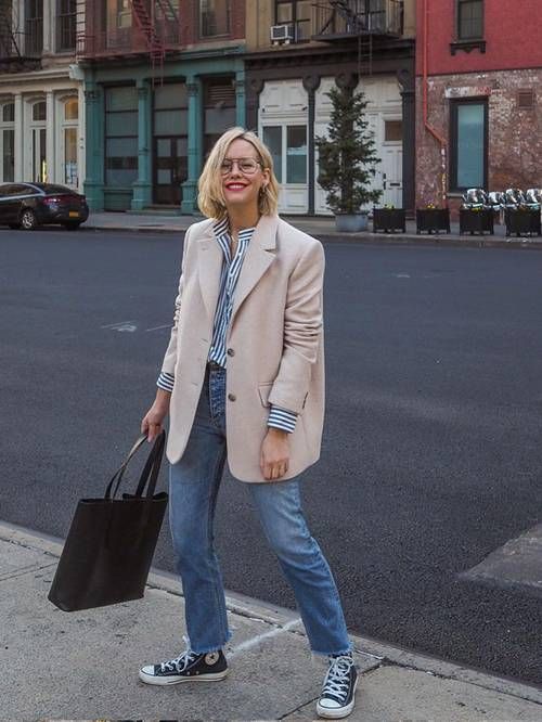a striped shirt, a tan oversized blazer, blue jeans, navy sneakers and a black tote for a casual work look