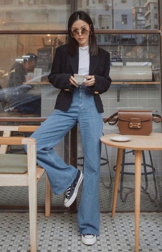 a white t-shirt, a black blazer, blue high waisted flare jeans, black sneakers and a chain necklace plus a chic brown bag