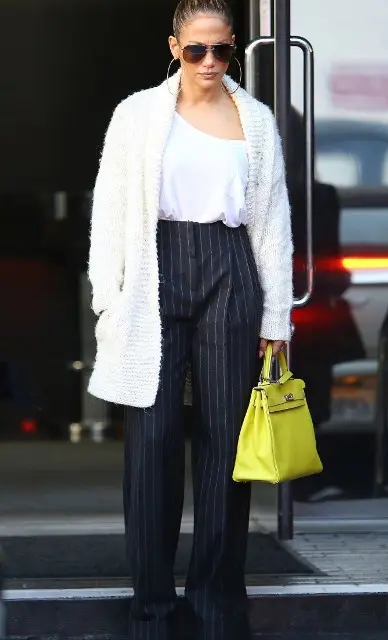 With golden rounded earrings, sunglasses, white one shoulder top, yellow tote bag and high heels