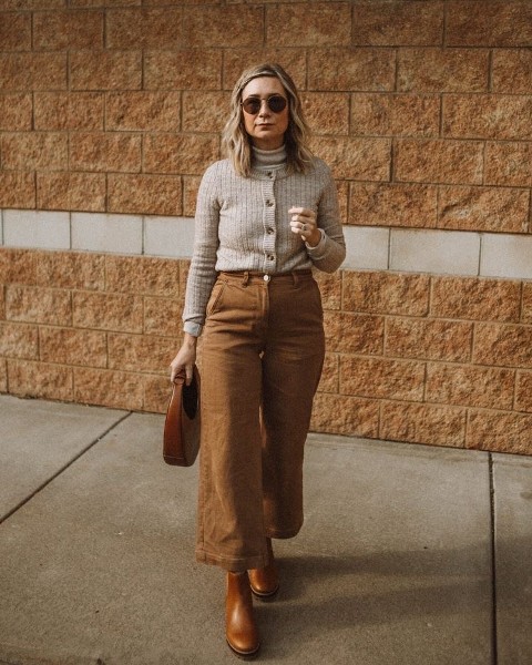 With rounded sunglasses, gray turtleneck, brown leather bag and brown leather flat ankle boots