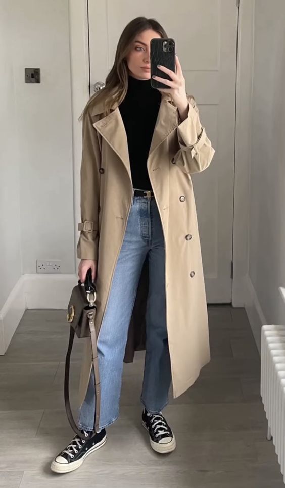 a black turtleneck, blue jeans, black Converse sneakers, a black belt, a beige trench and a brown bag for spring or fall