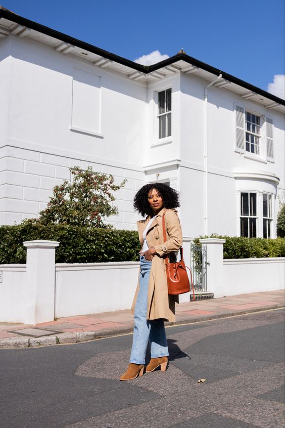a white t-shirt, blue jeans, rust-colored boots, a beige trench and an amber bag are a lovely look for spring